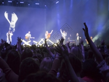 韵律流行音乐照明观众用双手在音乐节上举起手来灯光从舞台上下流而图片
