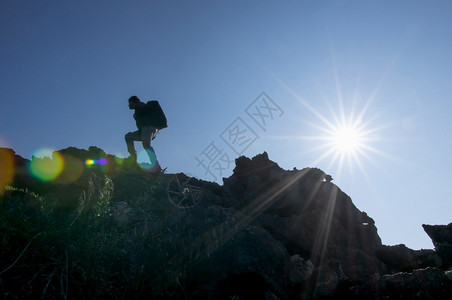 一个年轻的背包男在一个明亮的日光照耀着美丽的阳光下徒步旅行登山攀岩一个者轮廓风景日落背景图片