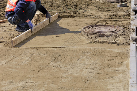 小路在下水道坑洞周围的人行道上工将沙质平台与木板对齐为铺的板块奠定基础工人将沙质地基与木板对齐在人行道上的下水井口四周铺设砖头为背景图片