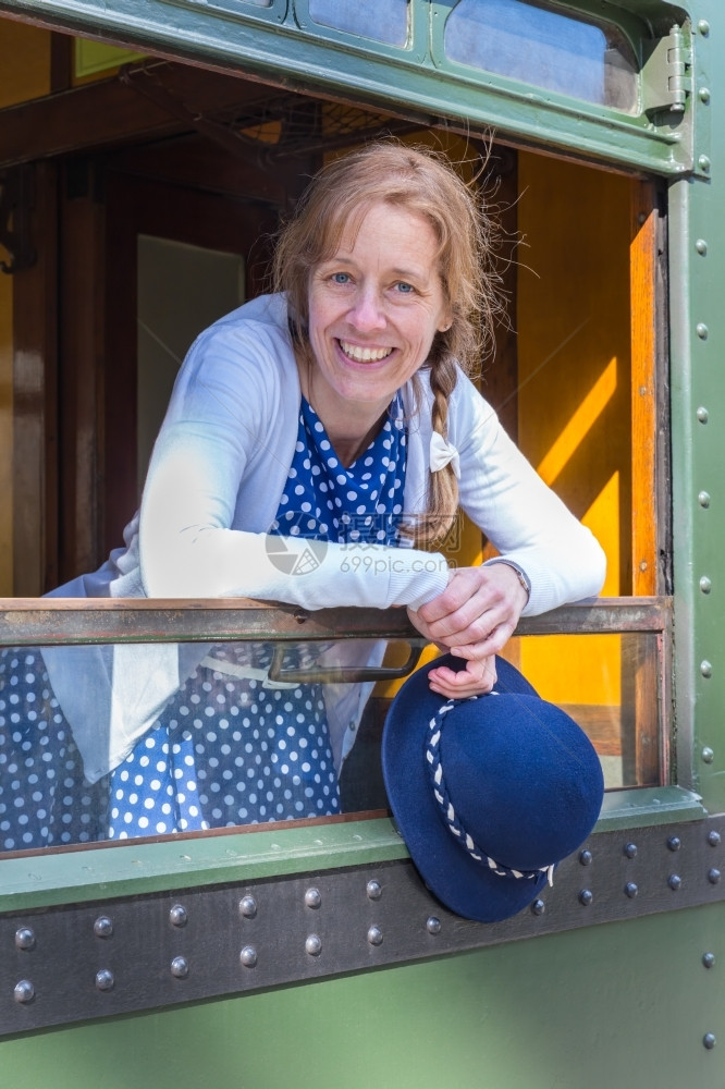 解放成人帽子身着蓝色的旧式衣服戴着火车窗顶帽的高加索中年妇女图片