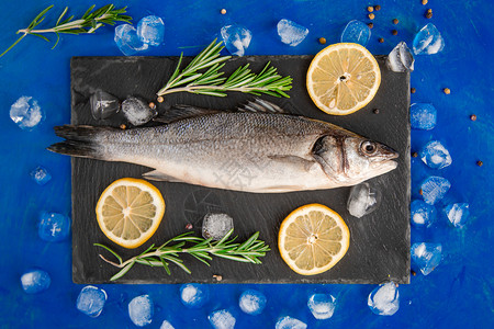 美食寒冷的白鱼黑石板上生鲈配香料和草新鲜的鲈鱼顶视图带复制空间食物高清图片素材