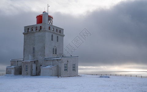 拂晓环境Dyrholaey角灯塔全景图像冰雪和清晨光照冰岛冬季海滨图片