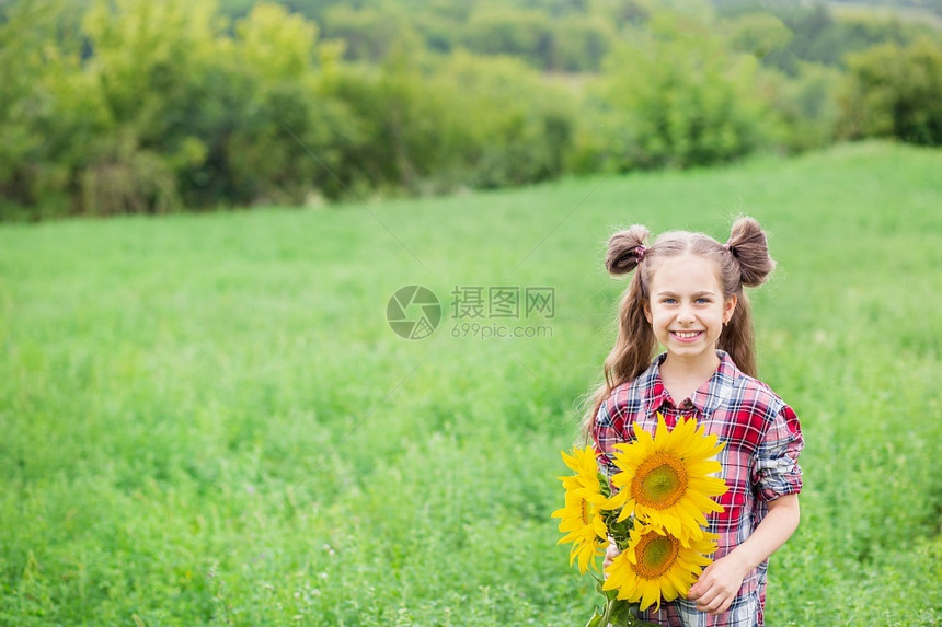 年轻的快乐一个穿成格子衬衫的小女孩肖像手上握着一束向日葵花在背景上画着一个小女孩的肖像手里拿着大漂亮的向日葵花束景观图片