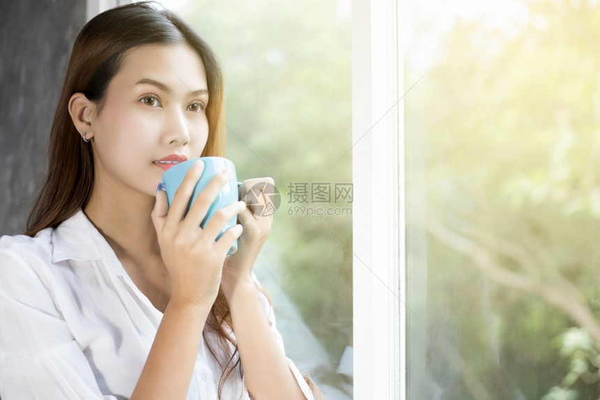 杯子快乐的早餐亚裔妇女喝咖啡在床上醒来后完全休息清晨打开窗帘以获得阳光的新鲜空气亚洲妇女喝咖啡在床上醒来图片