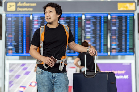 曼谷超过在现代机场旅行和运输概念的飞行信息屏幕登入飞行信息屏幕时有护照行李的亚洲旅者在飞板上站立机牌的亚洲旅行者肖像朋友们航班高清图片素材