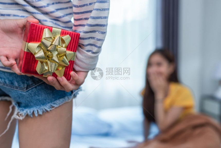 女朋友近亲手握着礼物给卧室里的女友惊喜人和概念生活方式与幸福概念女者主题以及男者主题背部婚礼图片