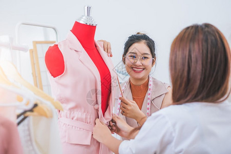 卖亚洲有吸引力的时装设计师亚洲女时装设计师工作向顾客裁缝和纫服装匠提出店模特品的新设计收集服装建议生活方式概念裙子愉快购买高清图片素材
