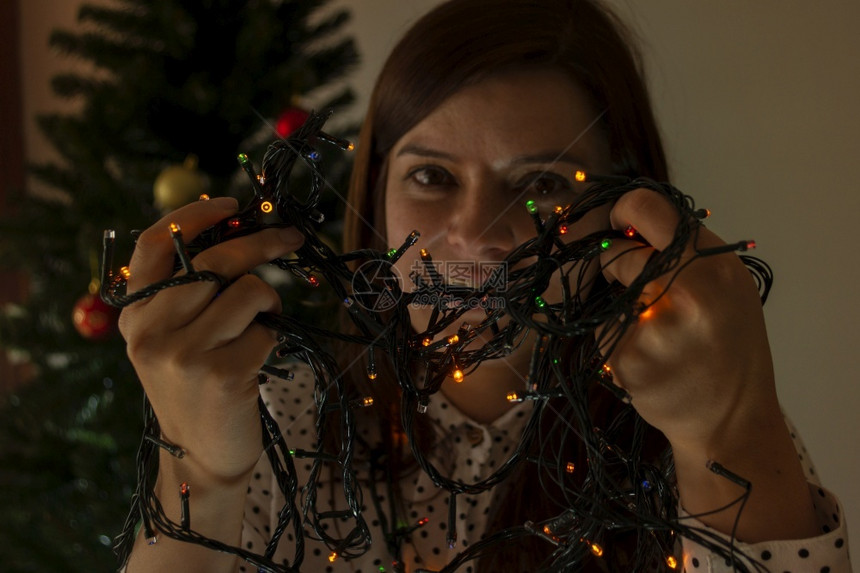 特写一个微笑的女人脸用红色绿和蓝的灯光来装饰她手中的圣诞树假期厄瓜多尔音乐图片