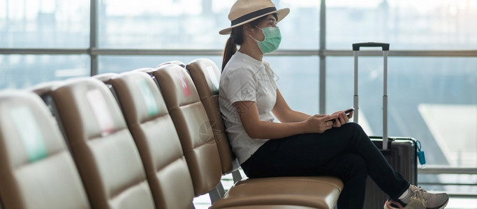 戴着口罩在机场等候登机的女游客图片