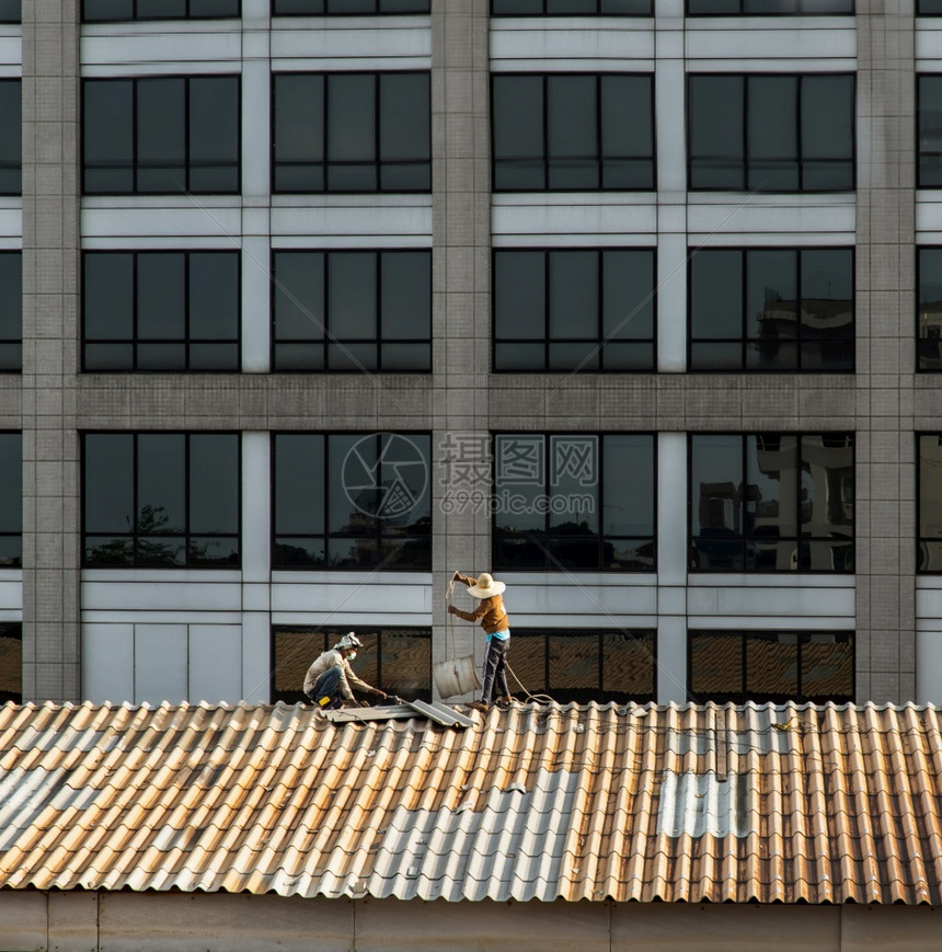 泰国曼谷201年5月日两名打杂工人在被损坏的工厂屋顶上修理瓷砖损害人们带状疱疹图片