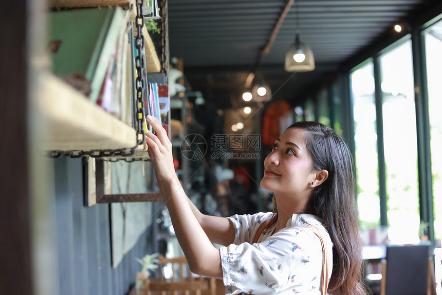 亚洲女选择书阅读和笑的在咖啡店放松模型教育保持图片