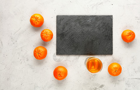 石板由灰白制成的切割周围环绕着黑桃橙子水果这些实随机地放在附近的灰色混凝土背景上复制灰蓝板的空间切割它位于灰红混凝土背景上整个橘背景图片