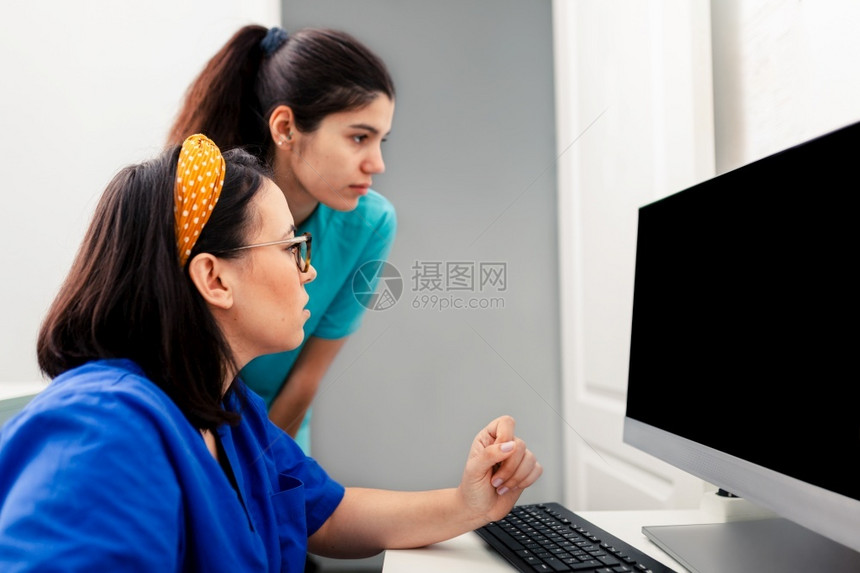 合作审查桌子两名护士在X光室使用计算机其中一名佩戴眼镜坐在书桌附近2名护士在X光室使用计算机2名护士在X光室使用计算机图片