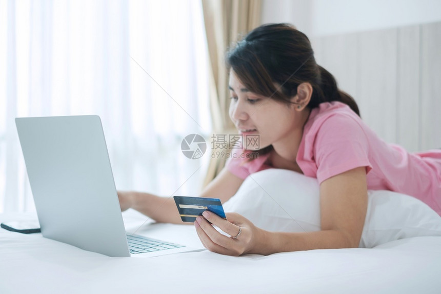 拥有信用卡并使电脑笔记本在线购物的快乐妇女同时上午在家中床下订单商业技术电子商务数字银行和网上付款概念经营数字银行和网上付款概念图片