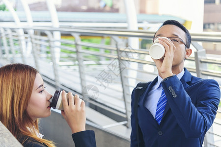 女士商界人在办公室外的镇子喝咖啡现代城市手举拿掉咖啡杯一起聊天愉快伙伴生意人正式西装加一杯咖啡咖啡因现代的套装高清图片素材