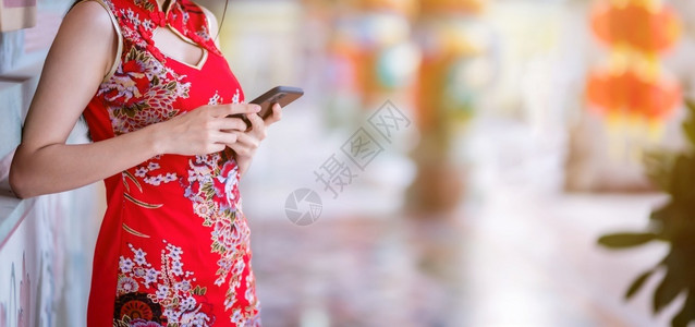 身着红色传统青山装饰的紧贴亚裔年轻女子在泰国华神庙新年节中写文智能手机贺词i支付保持成人背景