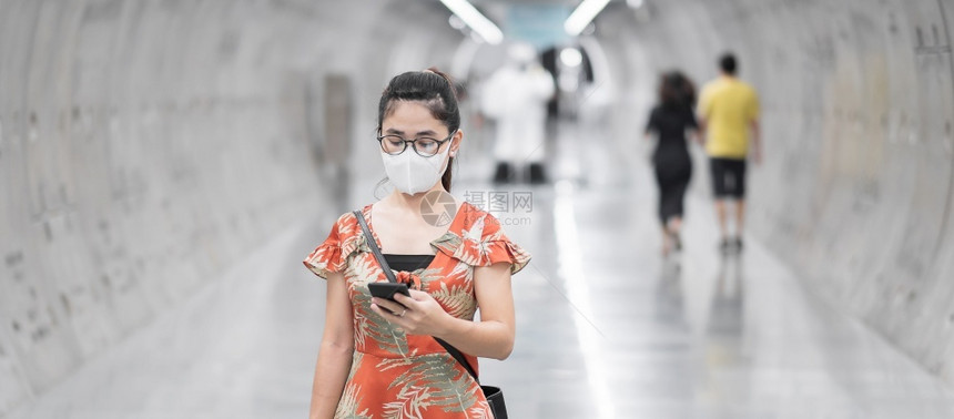 地铁站戴口罩看手机的女士图片