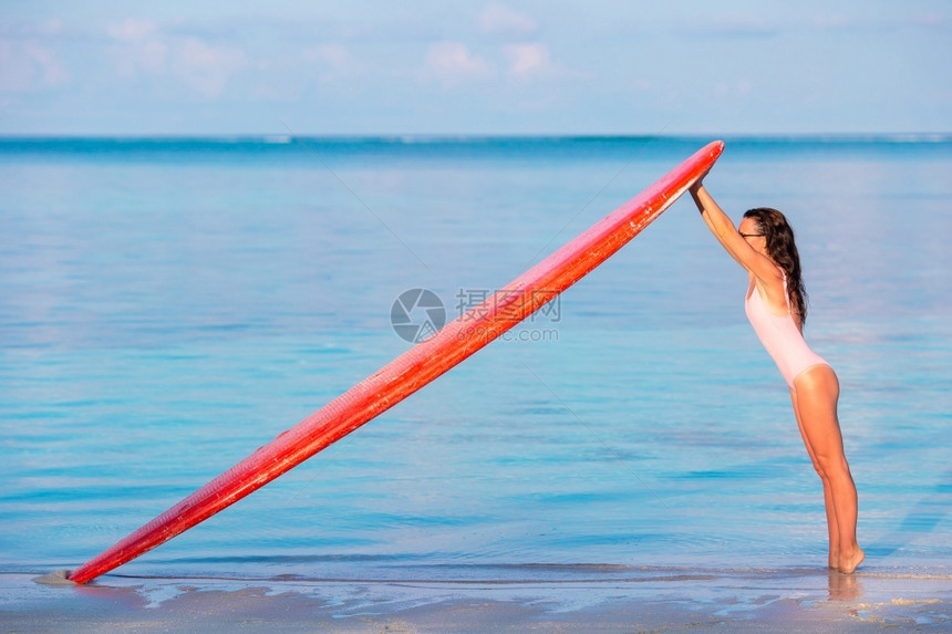 健康热带站立海上的冲浪女人和在马尔代夫的冲浪板在海滩玩得开心美丽的冲浪女孩和她板图片