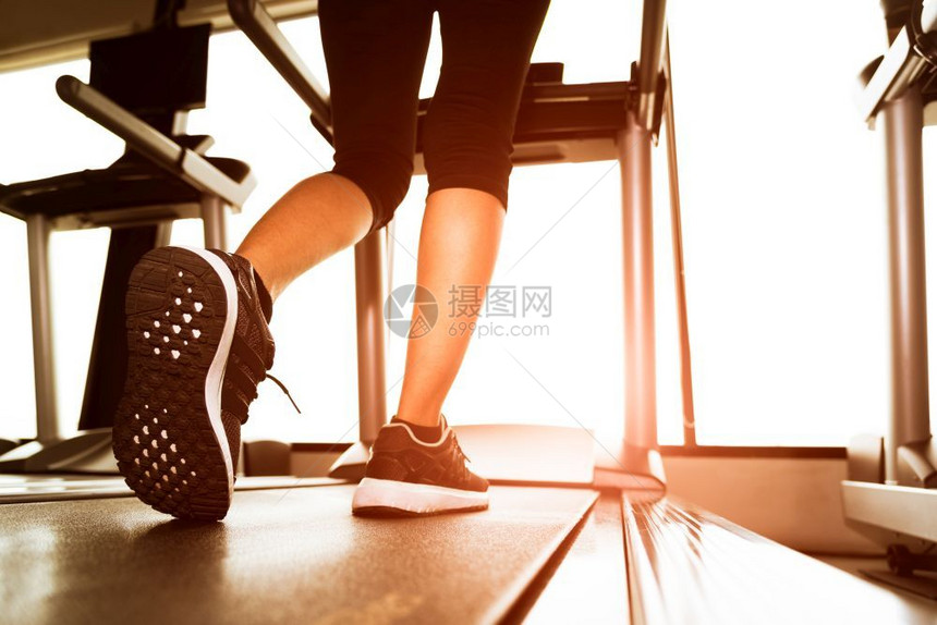 健身运动场机车或跑步上运行的健身女孩下体腿背影以太阳射线温暖的调子健康与锻炼活动概念健身与力量培训主题鞋饮食健身房图片