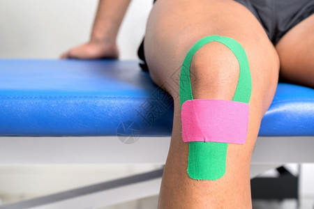 O型腿年轻的运动型男员用型胶带治疗受伤的膝盖特写运动学物理疗法康复概念疼痛肌肉发达嬉戏的背景