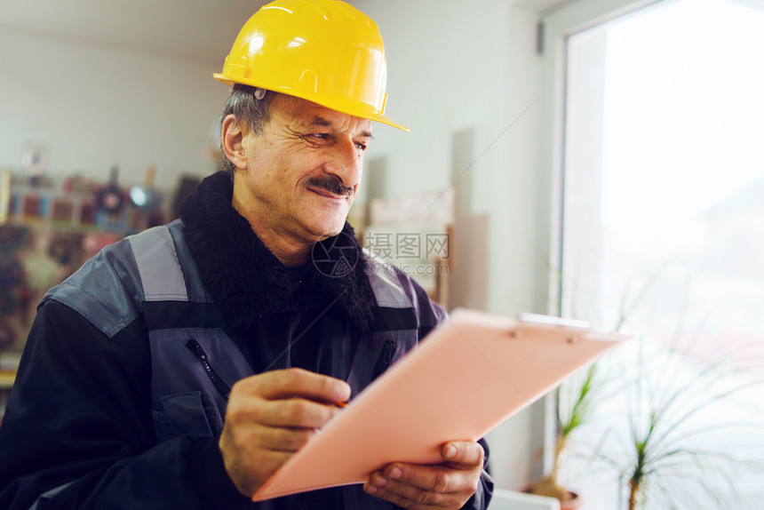 控制经理材料Caucasian高级男子建筑工一般人建筑承包商的肖像他们身着黄色保护头盔手持钢笔和办公室仓库数据报告项目的文件核对图片