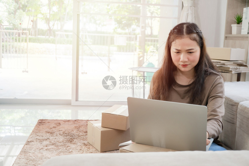 笔记微笑中小企业不快乐的亚洲年轻企业家疲倦的表达和厌在家办公的问题在线商户业务和电子的概念图片
