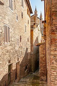 纪念碑文化城市的意大利马尔凯乌比诺文艺复兴小镇从意大利马尔凯乌比诺市一条狭窄的街道上可以看到公爵宫的景色背景图片