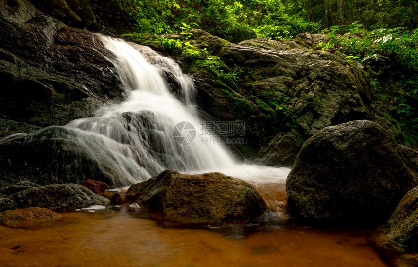植物热带森林中充满绿树和阳光的瀑布林中自然背景的瀑布正在流动岩石或瀑布中的头在泰国绿色季节旅行绿色季节在泰国旅游叶子郁葱图片