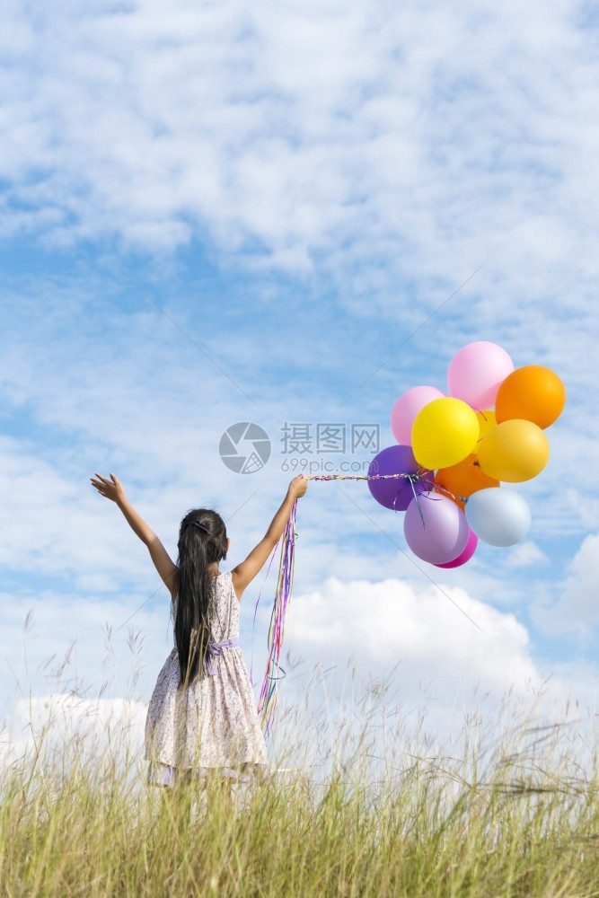 快乐的可爱女孩拿着气球在绿色草地白云和蓝天空上运行快乐的天空手拿着充满活力的空气球在生日派对上玩欢乐的可爱女孩愉快保持士图片