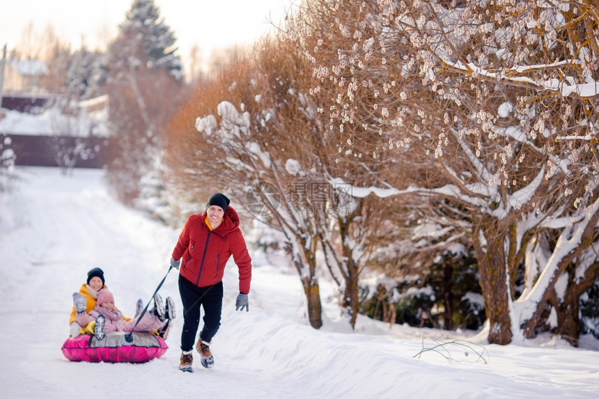 围巾父亲和孩子的幸福家庭骑着管子在冬季户外玩得开心父亲和孩子们在圣诞节前夕渡假的家庭父亲和孩子们在圣诞夜室外度假的家庭活动一种图片