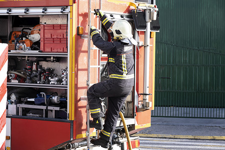 职业紧急情况装备齐全的消防员爬上车梯制服图片