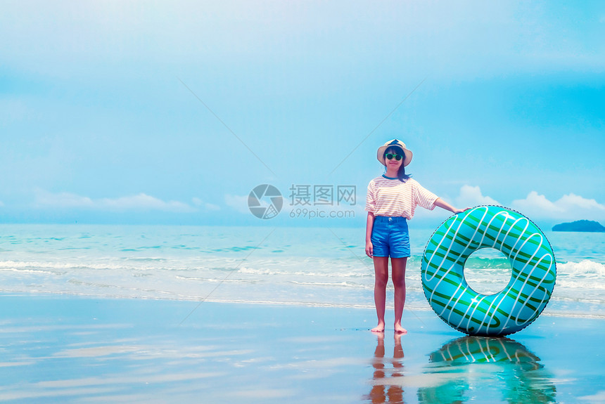 保持夏日海滨上可爱的亚洲女孩拿着游泳环戴帽子眼镜和快乐笑暑假中人们都在度支撑休息图片