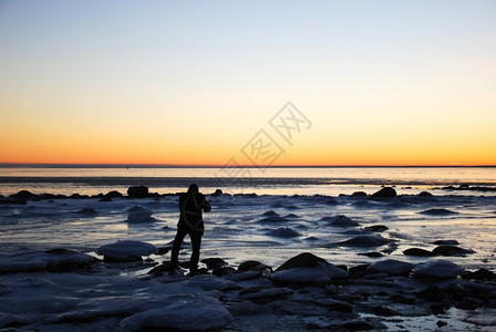 美丽的冰河海岸日落前有拍摄人影的男子身户外岩石图片