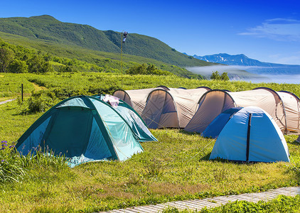 旅游者在山坡边湖岸的树林中扎营背景图片