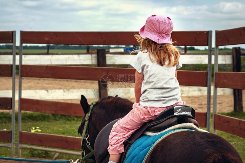 牧场骑马年轻女孩作为骑马的后背女孩将童视为骑马者课程让小孩回过头来看运动和娱乐与春或种马活动术图片