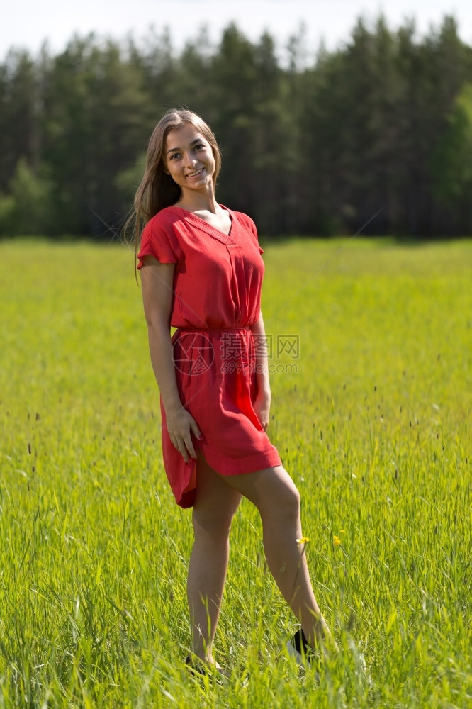 春天在阳光明媚的一天穿着红礼服在田野里户外吸引人的图片