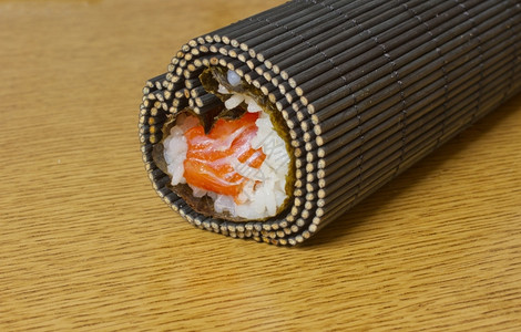白饭海藻煮寿司杂草大米和鲑鱼卷在垫子上红色的图片