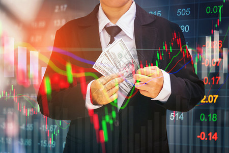 数字的在股票市场金融交易所信息和贸图背景上持有美元钞票的实业家商员富有的现金设计图片