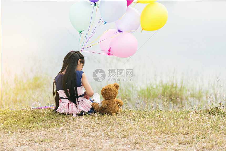 阳光手飞行快乐的小孩拥抱泰迪熊在绿公园操场拿着气球泰迪为小可爱的自闭症女孩交最好的朋友玩得开心一起在操场上握着多彩气球图片