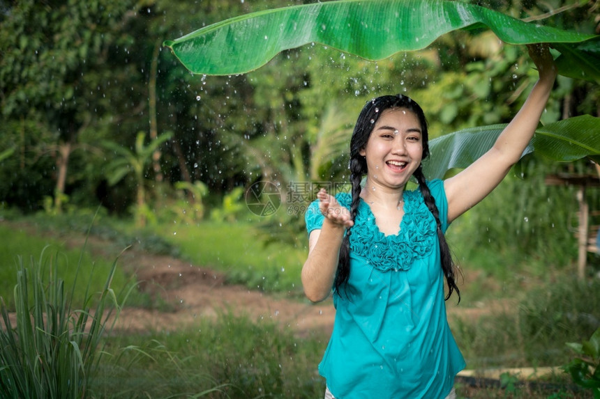 在绿花园背景下雨时一位年轻亚洲女身着香蕉叶的黑头发肖像乡村美丽的户外图片