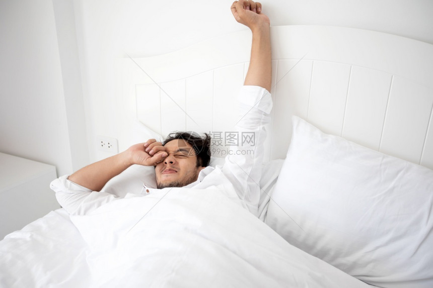 成人钟一个男醒来时躺在床上完全休息早上打开窗帘呼吸新鲜的空气得到图片