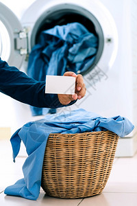 烘干机服饰男子在装有洗衣机背景的洗涤机篮子衣服上持有空名片的人丝绸房间高清图片素材