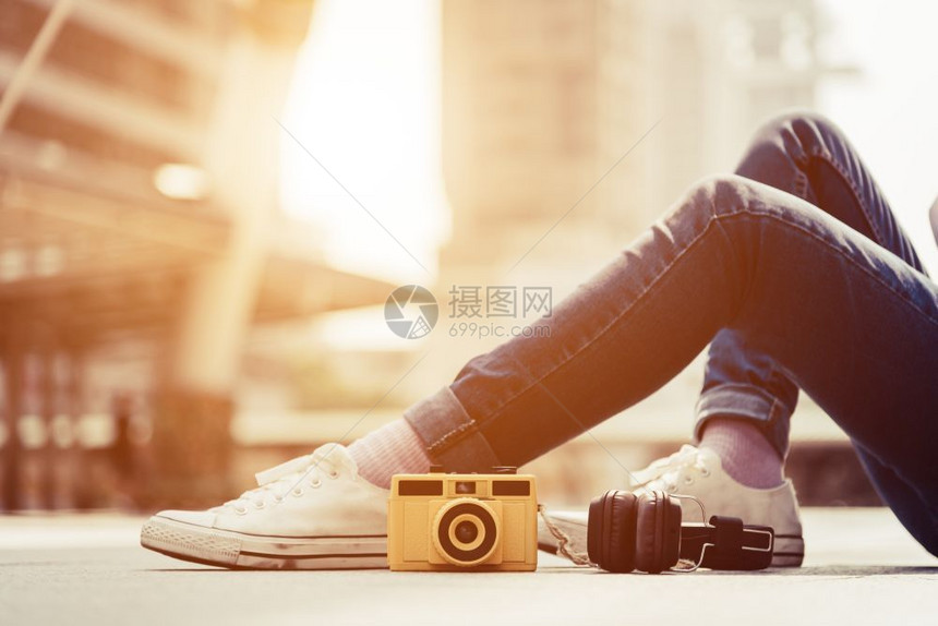 穿着牛仔裤在市中心休息和放松的女子腿穿牛仔裤在城市中间休息和放松在城市中时装照相机和Stereo耳语元素时装和现代技术概念优质的图片
