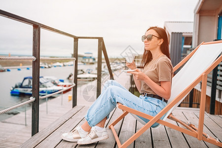 白色的年轻女子喝热咖啡欣赏海滩美景茶女士图片