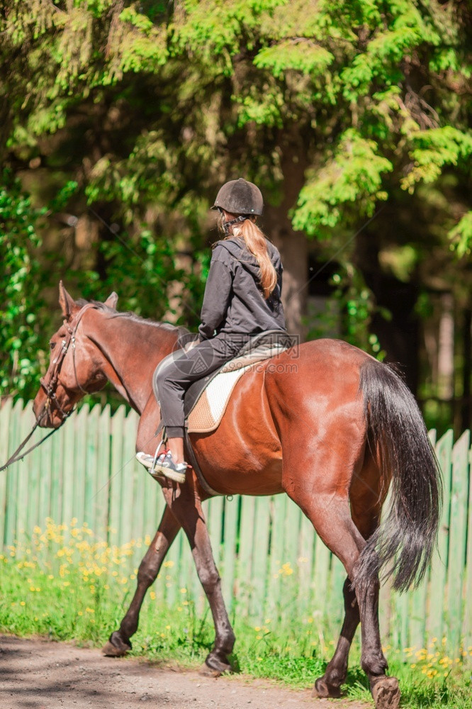 青少年速度驰骋在公园小路上骑黑马的女孩在公园小路上骑马的女孩图片