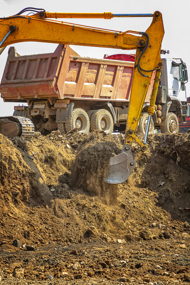 行业户外地球在建筑工施的黄色挖土机和空倾卸车垂直视线图片