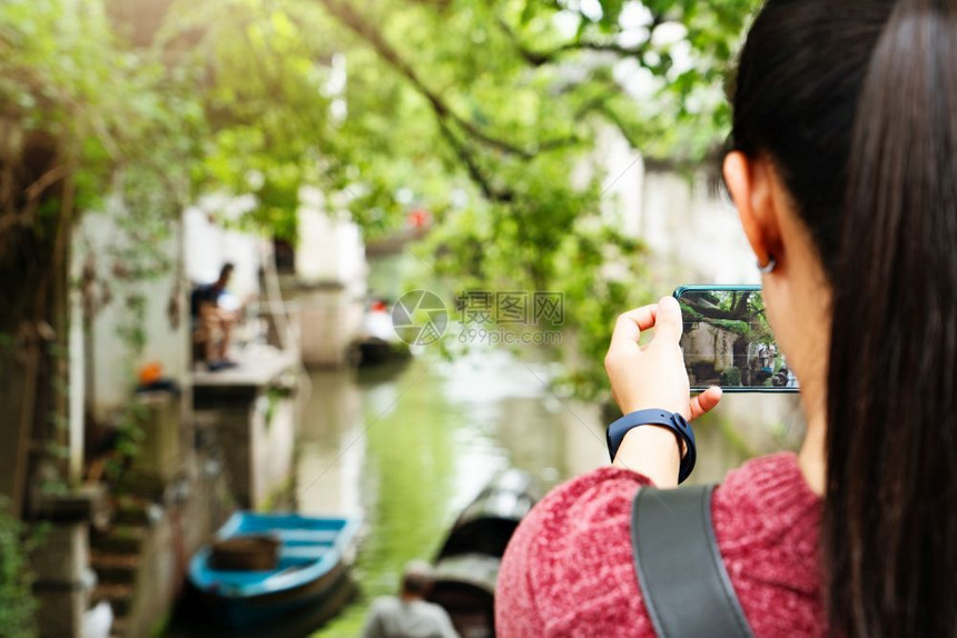 夏天活的在本地运河城市玩得开心的年轻女子使用智能手机摄影拍照片乐趣图片