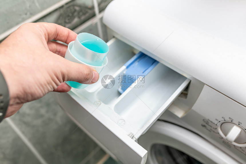 效用家庭填充男手把洗衣涤剂倒进机然后在涤剂上浇水图片