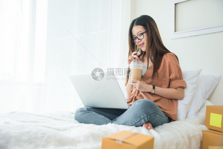 使用笔记本电脑和在床上喝咖啡的亚洲美女妇在床上用笔记本电脑以及商业和技术概念交付和在线购物概念快乐的美丽服务图片