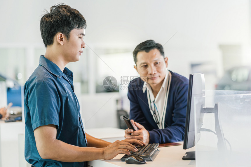 优雅的亚洲机械工打键盘时为客户提供服务在展厅的维护服务中心检查时打键盘职业专的图片